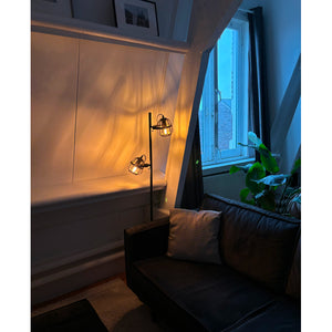 Die braune Stehleuchte Nature Trapeze bringt ländlichen Charme ins Wohnzimmer.